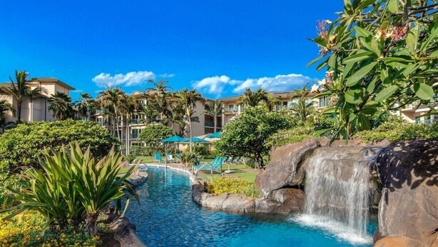 A resort with a swimming pool, palm trees, and a waterfall. - Waipouli Beach Resort | Spacious 2BD Retreat -Lazy River, Spa & Central Location (Kapaa)