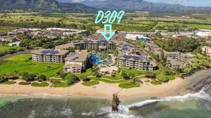 A resort with multiple buildings, a beach, and mountains in the background. - Waipouli Beach Resort | Spacious 2BD Retreat -Lazy River, Spa & Central Location (Kapaa)