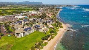 An aerial view of a coastal resort with multiple buildings, a beach, and clear blue waters. - Waipouli Beach Resort | Spacious 2BD Retreat -Lazy River, Spa & Central Location (Kapaa)