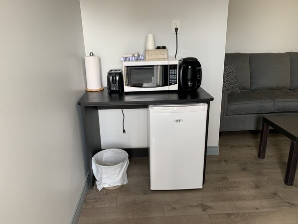 A compact kitchenette with a microwave, coffee maker, and a small refrigerator.