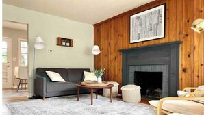 A living room with a grey sofa, a round wooden coffee table, and a fireplace.