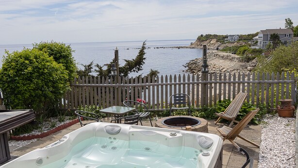 Un jardin avec un jacuzzi, du mobilier d’extérieur et une vue sur l’océan.