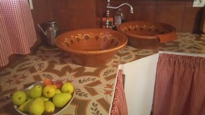 A kitchen with two large terracotta bowls, a bowl of fruit, and a sink with a faucet. - La Casita Verde Valle (Unknown)