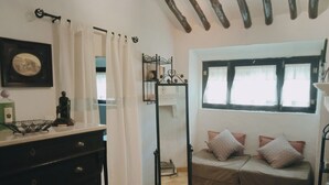 A cozy room with a bed, a dresser, a window with curtains, and a shelf with decorative items. - La Casita Verde Valle (Unknown)