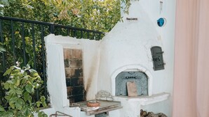 A patio with a table set for two, a white wall with a fireplace, and green chairs. - La Casita Verde Valle (Unknown)
