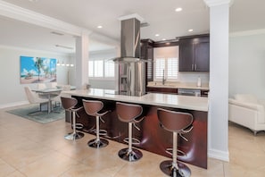 A modern kitchen with a central island, bar stools, and dark cabinetry.