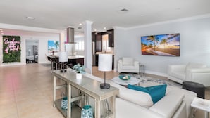 A modern living room with a white sofa, a coffee table, and a TV mounted on the wall.