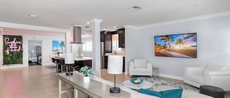 Una sala de estar moderna con un sofá blanco, una mesa de centro y un televisor montado en la pared.