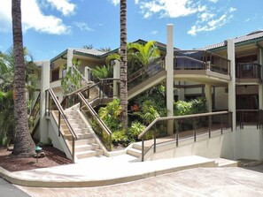A multi-level building with outdoor staircases, palm trees, and a clear sky. - Puunoa Beach Estates- Part OF Hyatt (LAHAINA)