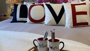A bedroom with a bed, pillows spelling "LOVE," a bedside lamp, and a tray with mugs and a note. - Romantic Private Getaway!  Hot tub, Fireplace and Views!  (Hopland)