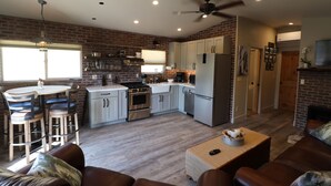 A spacious kitchen with modern appliances, a dining area with bar stools, and a cozy living room with leather sofas. - Romantic Private Getaway!  Hot tub, Fireplace and Views!  (Hopland)