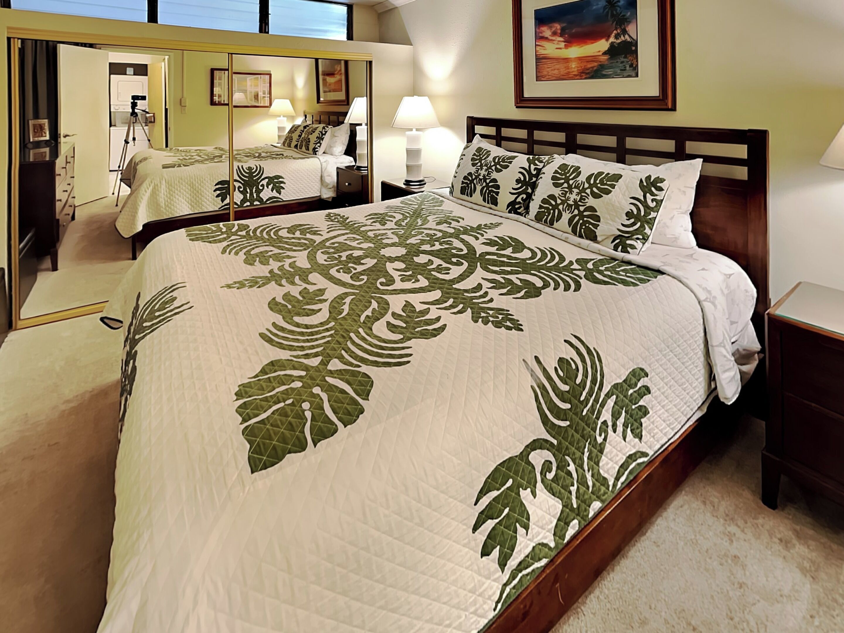 A bedroom with a large bed, a nightstand, a dresser, and a mirror.