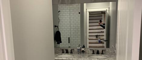 A modern bathroom with white cabinetry, a double sink vanity, and a tiled backsplash.