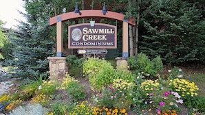 A sign for Sawmill Creek Condominiums with a garden of colorful flowers in front. - Ski-in condo off 4 O'clock, 1 block to Main St, steps to Gondola (Breckenridge)