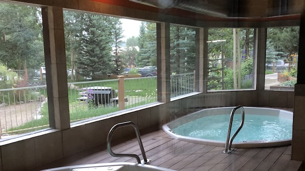 Two hot tubs in a wooden deck area with large windows overlooking a garden and a parking lot. - Ski-in condo off 4 O'clock, 1 block to Main St, steps to Gondola (Breckenridge)