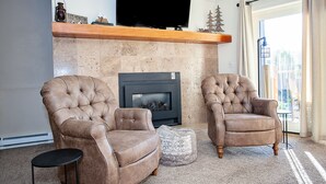 A living room with two brown leather armchairs, a fireplace, a television, and a view of the outdoors through a large window. - Ski-in condo off 4 O'clock, 1 block to Main St, steps to Gondola (Breckenridge)