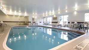 Una piscina con sillas de descanso y un cartel de socorrista.