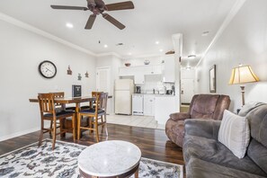 A spacious living room with a dining area, a kitchen, and a ceiling fan.
