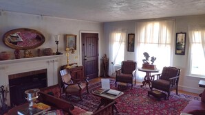 A traditional living room with a fireplace, wooden furniture, and a patterned rug.