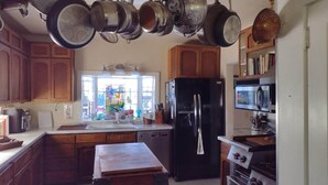 A kitchen with wooden cabinets, a black refrigerator, a microwave, and hanging pots.