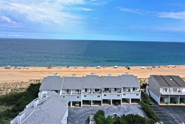 A beachfront hotel with multiple floors, a parking area, and a beach view.