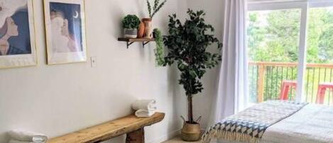 Une chambre avec deux lits, un ventilateur de plafond, une grande plante en pot et des œuvres d’art accrochées au mur.