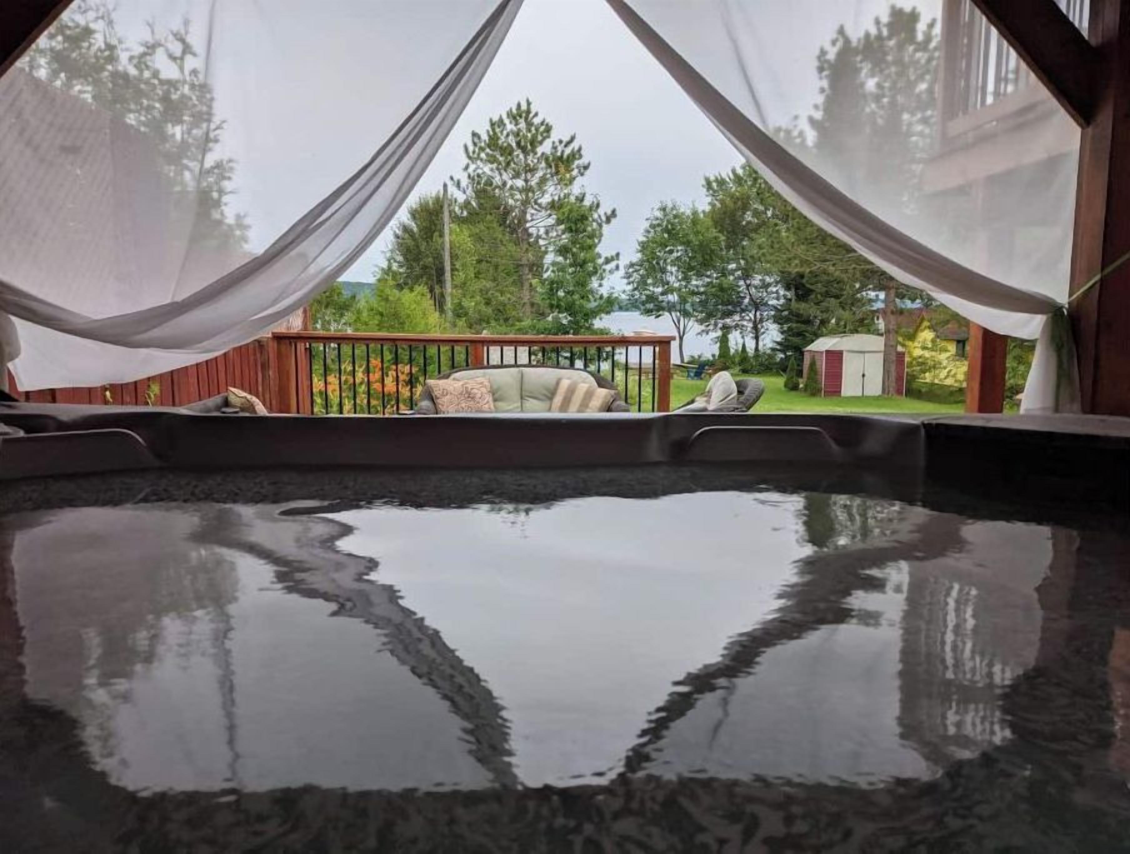 Un bain à remous avec vue sur une terrasse en bois et une pelouse.