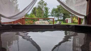 Un bain à remous avec vue sur une terrasse en bois et une pelouse.
