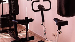 A gym with a stationary bike, a punching bag, and weightlifting equipment. - Praia da rocha, MArina. (Portimão)