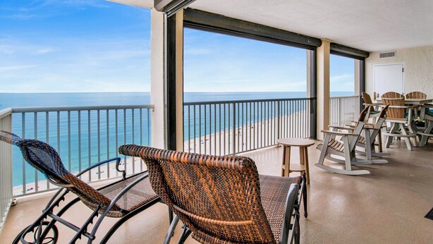 Un balcon avec des fauteuils en osier, une table et une vue sur l’océan.