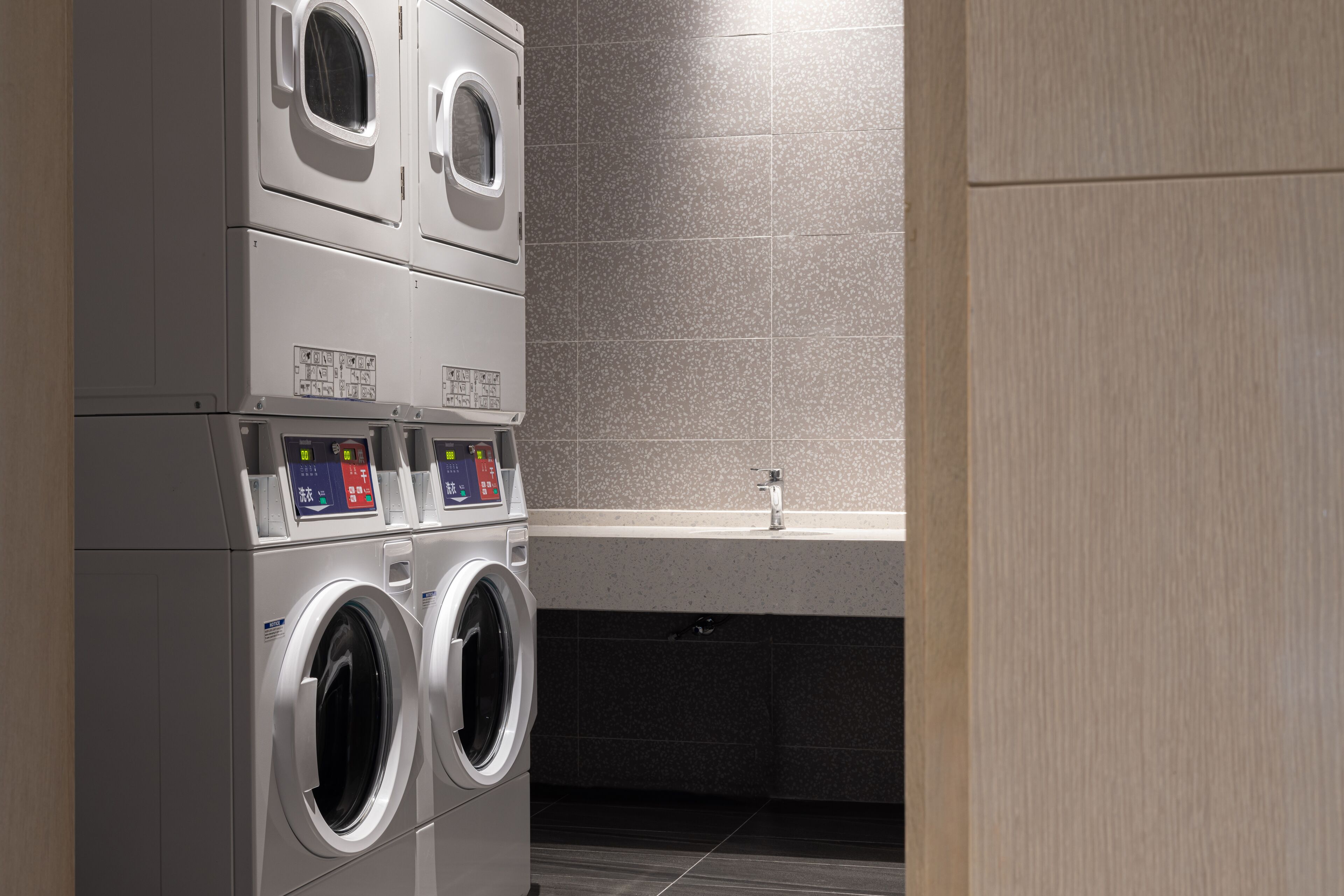 A laundry facility with stacked washing machines and a sink.