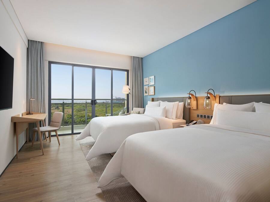 Et hotelværelse med to senge, et skrivebord og en stol.