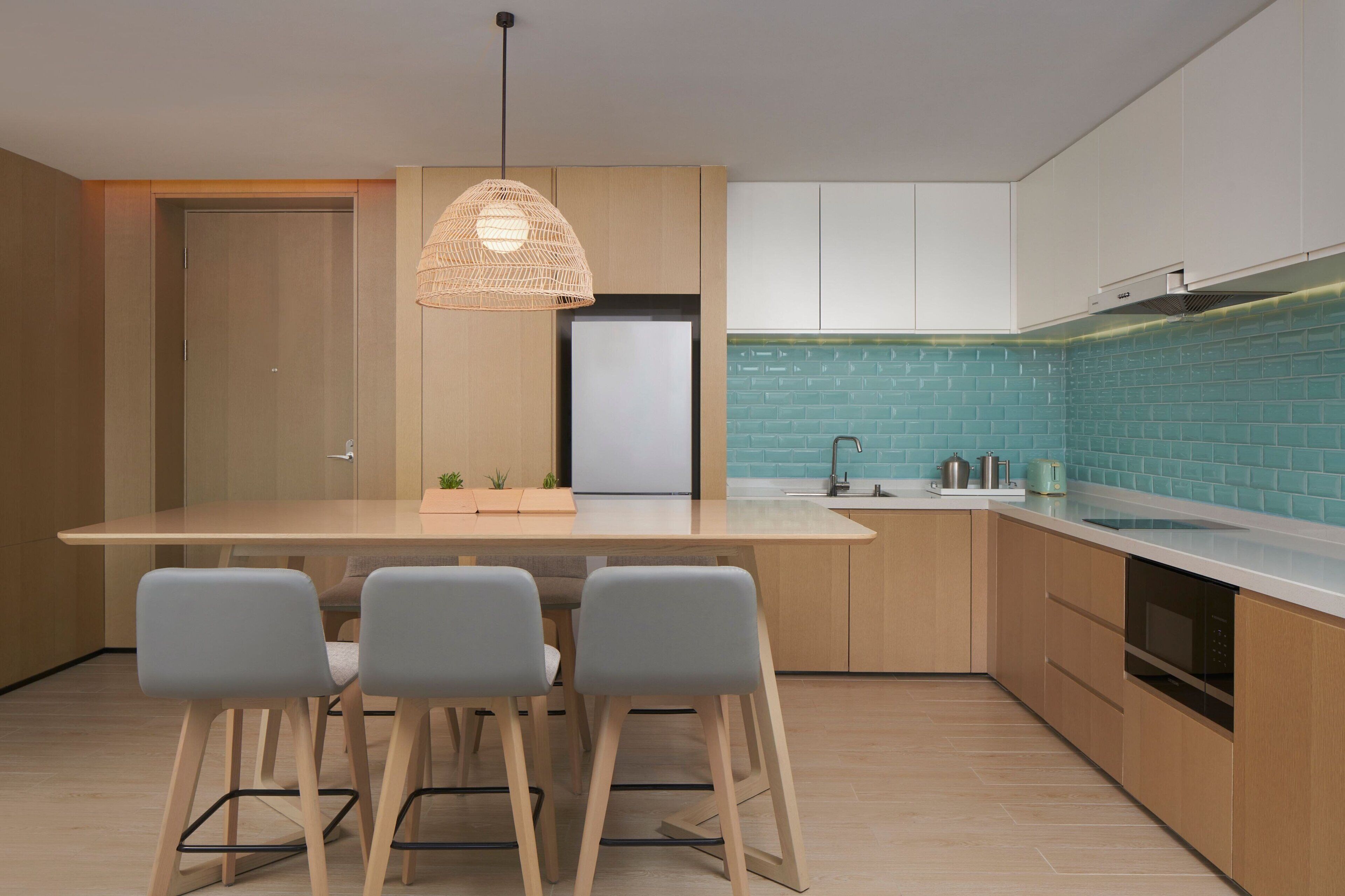 A modern kitchen with a central island, bar stools, a hanging light fixture, and a built-in oven.