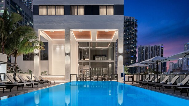 A modern hotel with a pool, lounge chairs, and a city skyline view. -  AC Hotel by Marriott Miami Brickell (Miami)