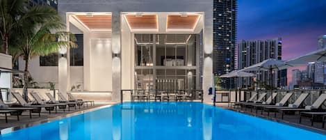 Una piscina al aire libre, camas de piscina gratis, sombrillas