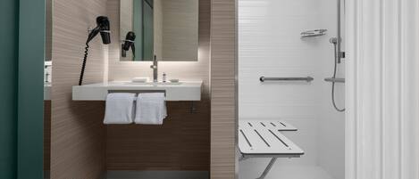 Un baño moderno con lavabo, espejo, toallero y zona de ducha.