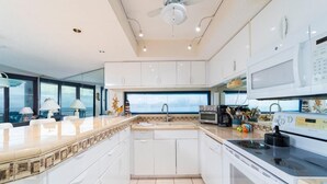 A modern kitchen with white cabinetry, a large window, and a built-in microwave. - Anastasia Condos Oceanfront – Spectacular Views & Great Rates! (Saint Augustine)