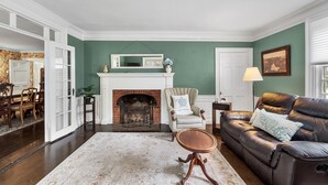 Un salon avec une cheminée, un canapé, un fauteuil et un coin repas avec des meubles en bois.