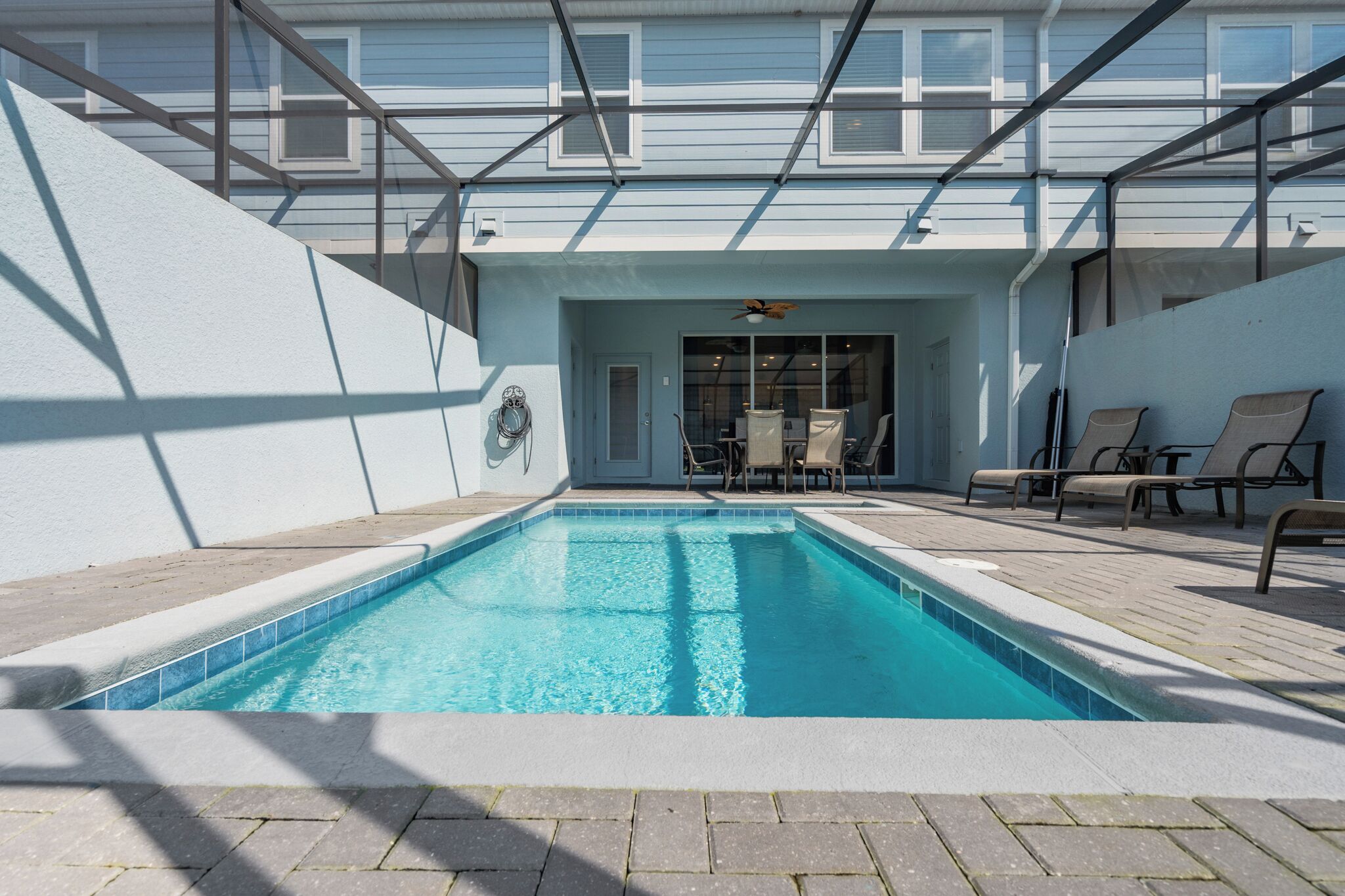 Une piscine avec des chaises longues et un espace salon abrité.