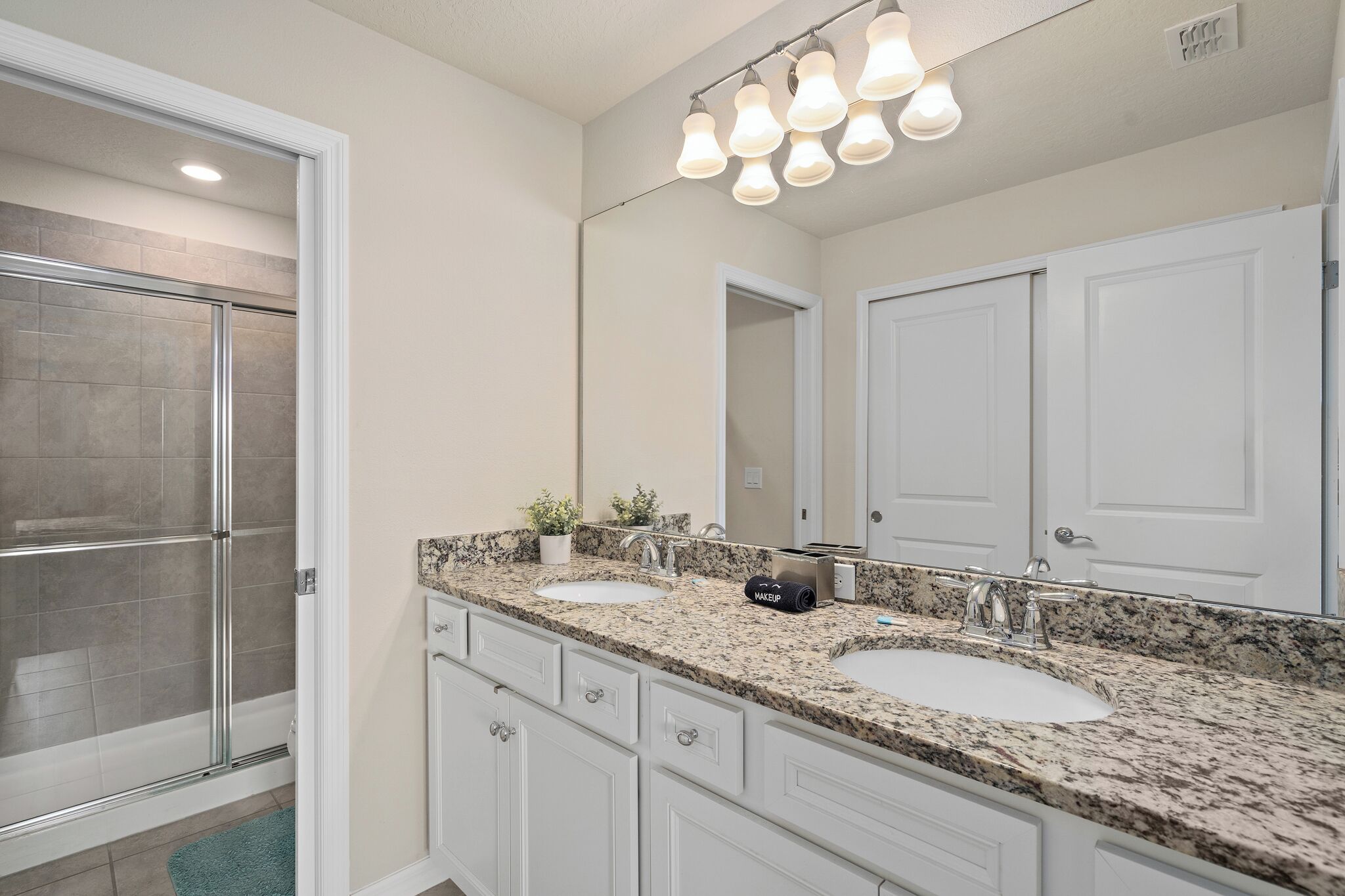 Une salle de bain avec deux lavabos, une douche et un grand miroir.
