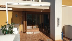 Un immeuble résidentiel doté d’un patio carrelé, d’une porte-fenêtre coulissante donnant sur un espace intérieur et d’un petit jardin.