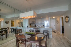 A modern kitchen with a central island, a dining area with a round table and chairs, and a large pendant light.