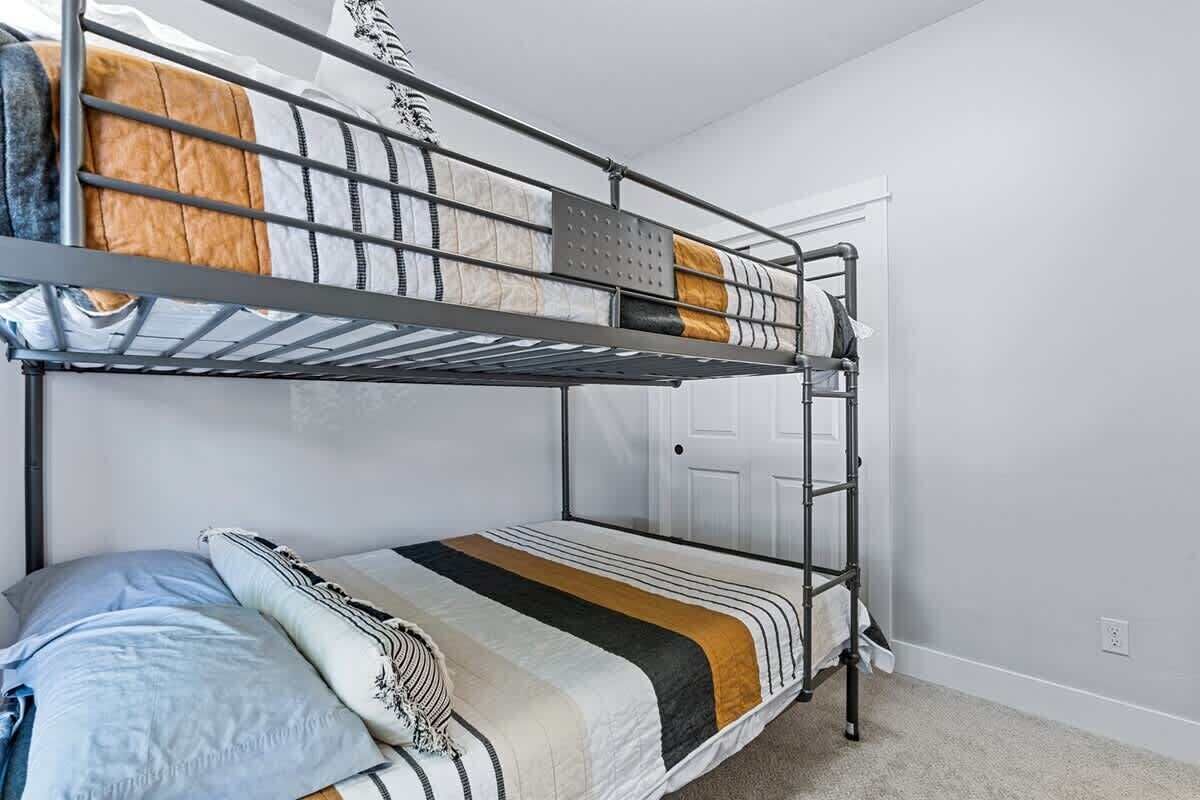 A bunk bed with a ladder, a door, and a carpeted floor.