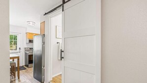 A kitchen with a sliding door, wooden cabinets, and a stainless steel refrigerator. - Downtown Caldwell | Golf Course View | Near I-84 | Fast WiFi | Sleeps 5 (Caldwell)
