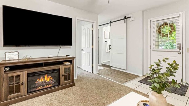 A living room with a flat-screen TV, a fireplace, a sliding door, and a door with a window. - Downtown Caldwell | Golf Course View | Near I-84 | Fast WiFi | Sleeps 5 (Caldwell)