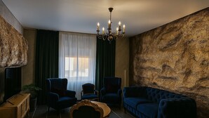Una sala de estar moderna con una araña, sofás azul oscuro y una pared grande con textura.