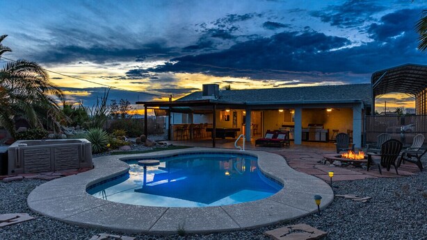 A pool area with a hot tub, outdoor seating, and a covered patio.