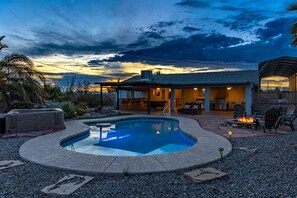 Uma área de piscina com hidromassagem, área de estar externa e alpendre coberto.