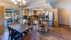A modern kitchen with wooden cabinets, a central island, and a dining area with chairs.