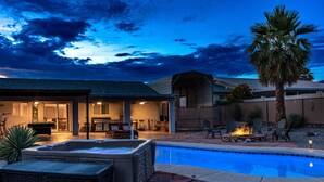 A backyard with a swimming pool, hot tub, and outdoor seating area with a fire pit.